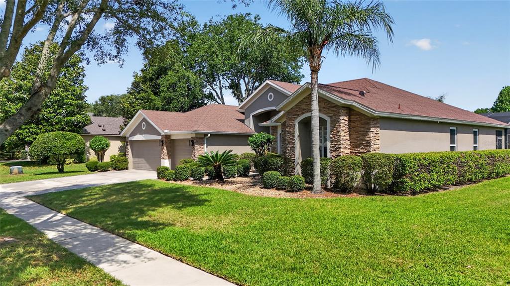 A single-story house with a stone facade, a palm tree, and a manicured lawn — 10354 OAKVIEW POINTE TERRACE, GOTHA, FL