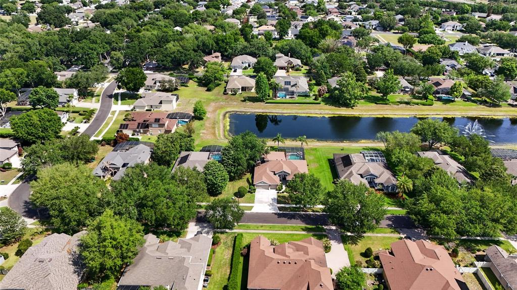 An aerial view shows suburban houses with swimming pools surrounding a central retention pond — 10354 OAKVIEW POINTE TERRACE, GOTHA, FL