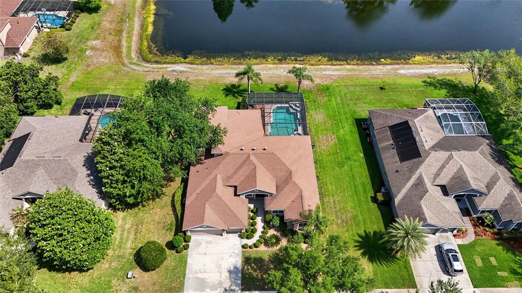 An aerial view shows three suburban houses with swimming pools and backyards facing a lake — 10354 OAKVIEW POINTE TERRACE, GOTHA, FL
