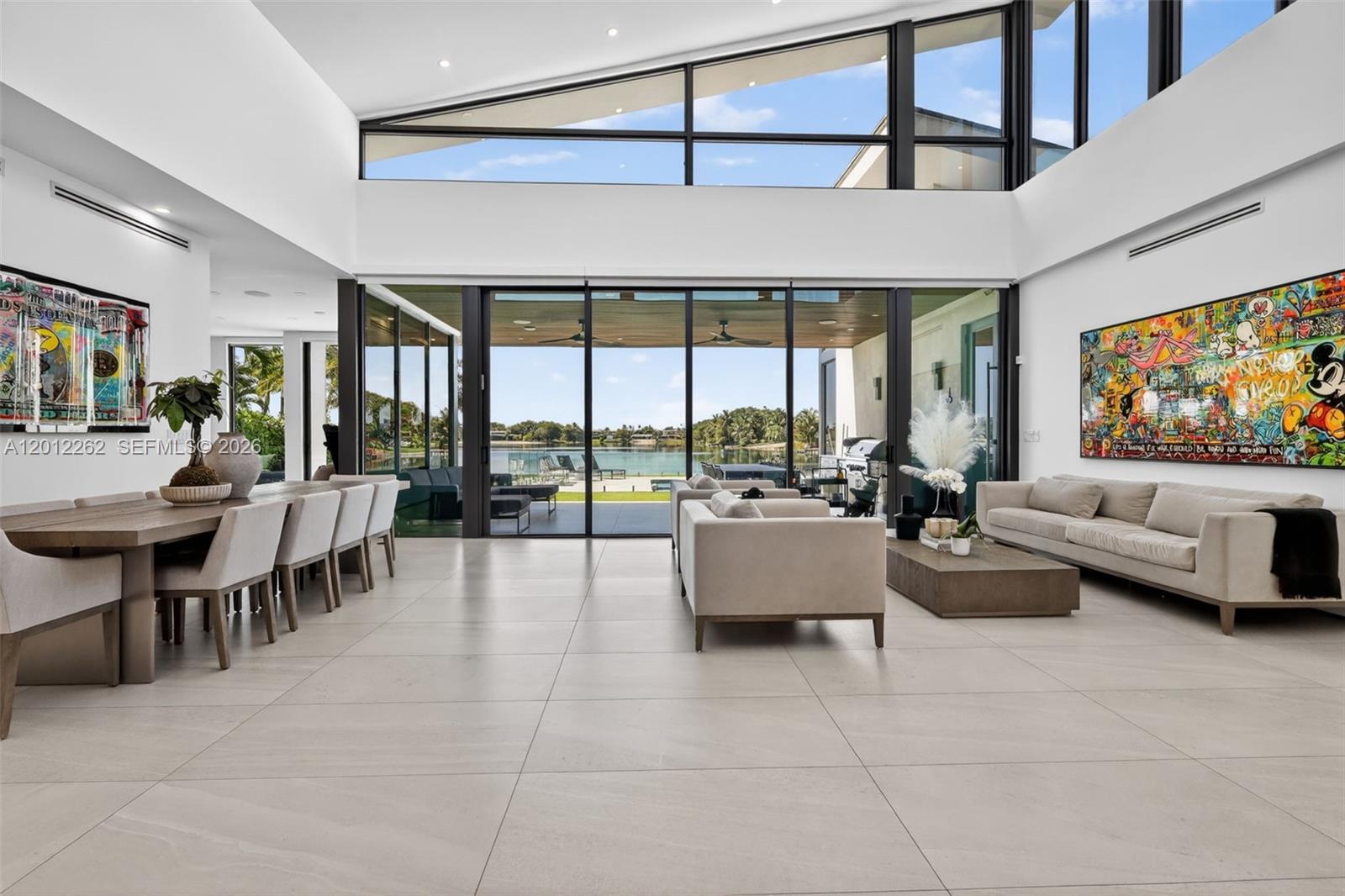 A modern open-concept living and dining area features high ceilings, large windows, and tile floors — 1830 NE 193rd St, Miami FL 33179, MIAMI, FL