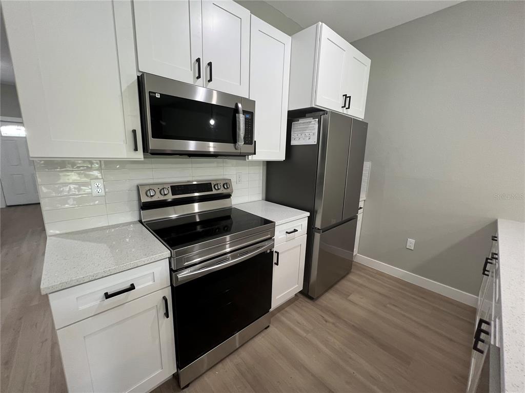 A kitchen features white cabinets, stainless steel appliances, and light-colored countertops — 12130 HENLEY AVENUE, PORT CHARLOTTE, FL