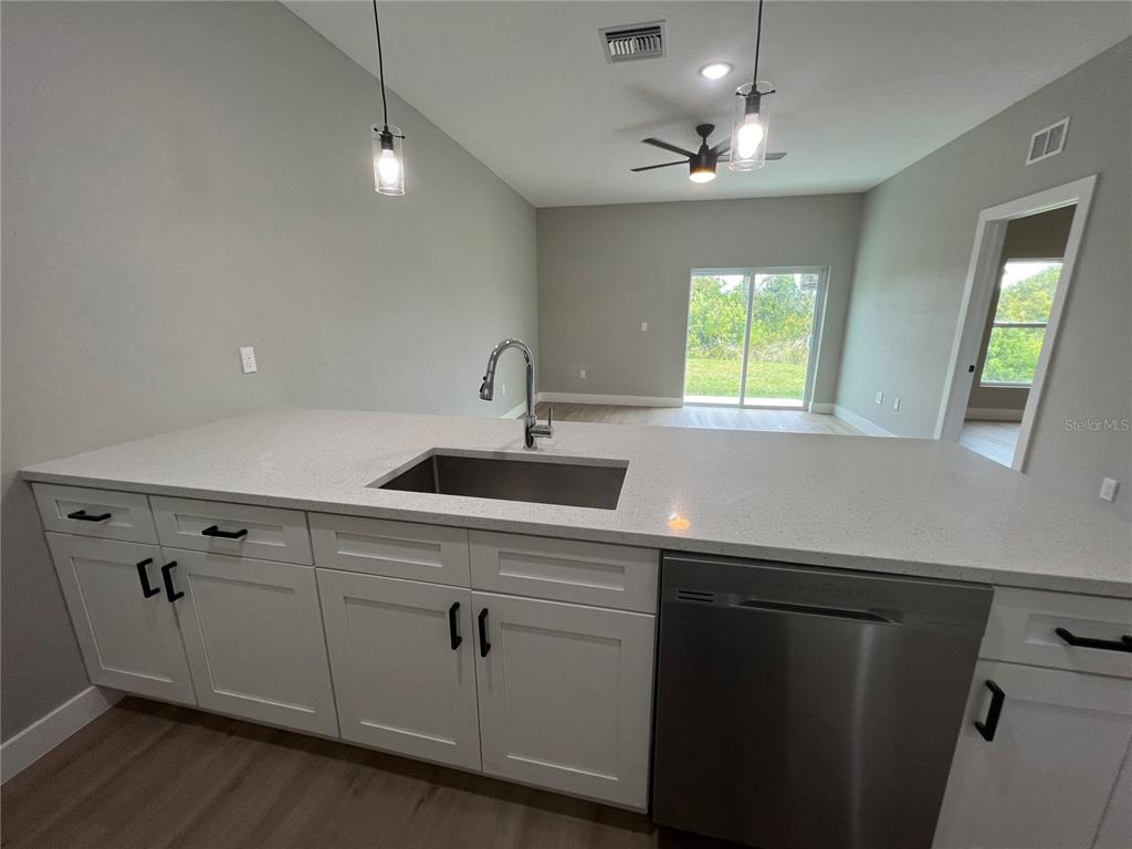 A kitchen island with a stainless steel sink and dishwasher faces an open living area — 12130 HENLEY AVENUE, PORT CHARLOTTE, FL
