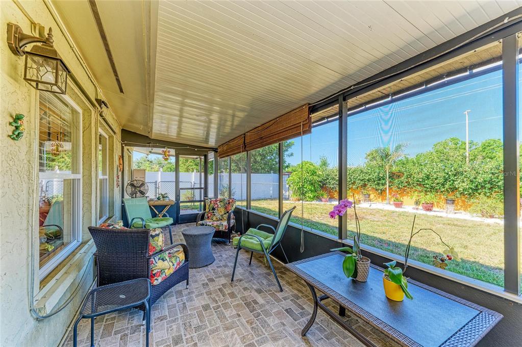 A screened-in patio with tiled flooring, patio furniture, and a view of a grassy backyard — 1768 BANYAN DRIVE, VENICE, FL