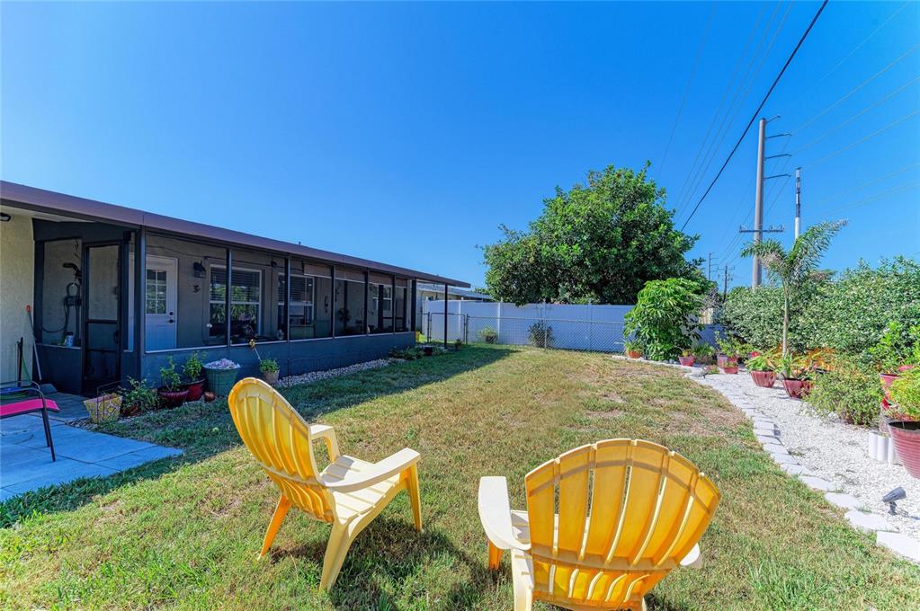 A backyard with a screened-in patio, two yellow chairs, and a white vinyl fence — 1768 BANYAN DRIVE, VENICE, FL