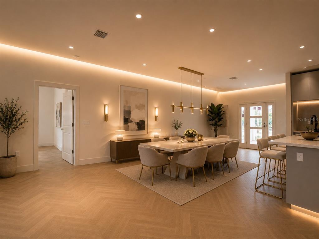 A dining area with a long table, upholstered chairs, and herringbone wood flooring — 7731 PINEDALE DRIVE, PORT CHARLOTTE, FL