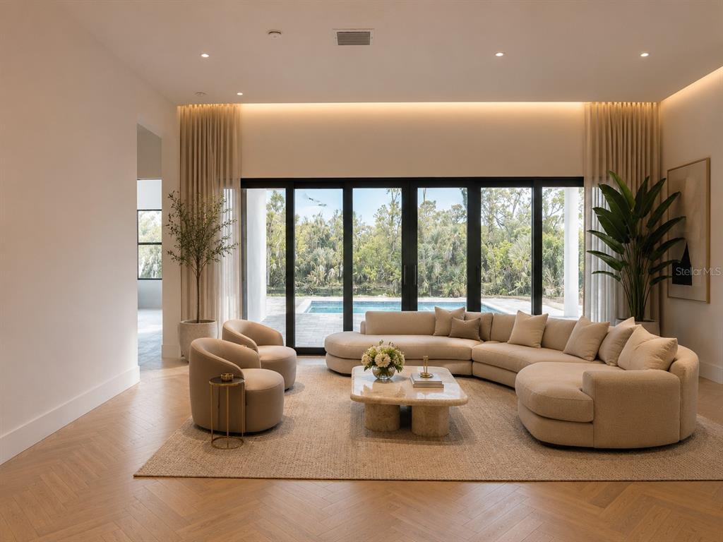 A modern living room features a curved sectional sofa, stone coffee table, and large glass doors — 7731 PINEDALE DRIVE, PORT CHARLOTTE, FL