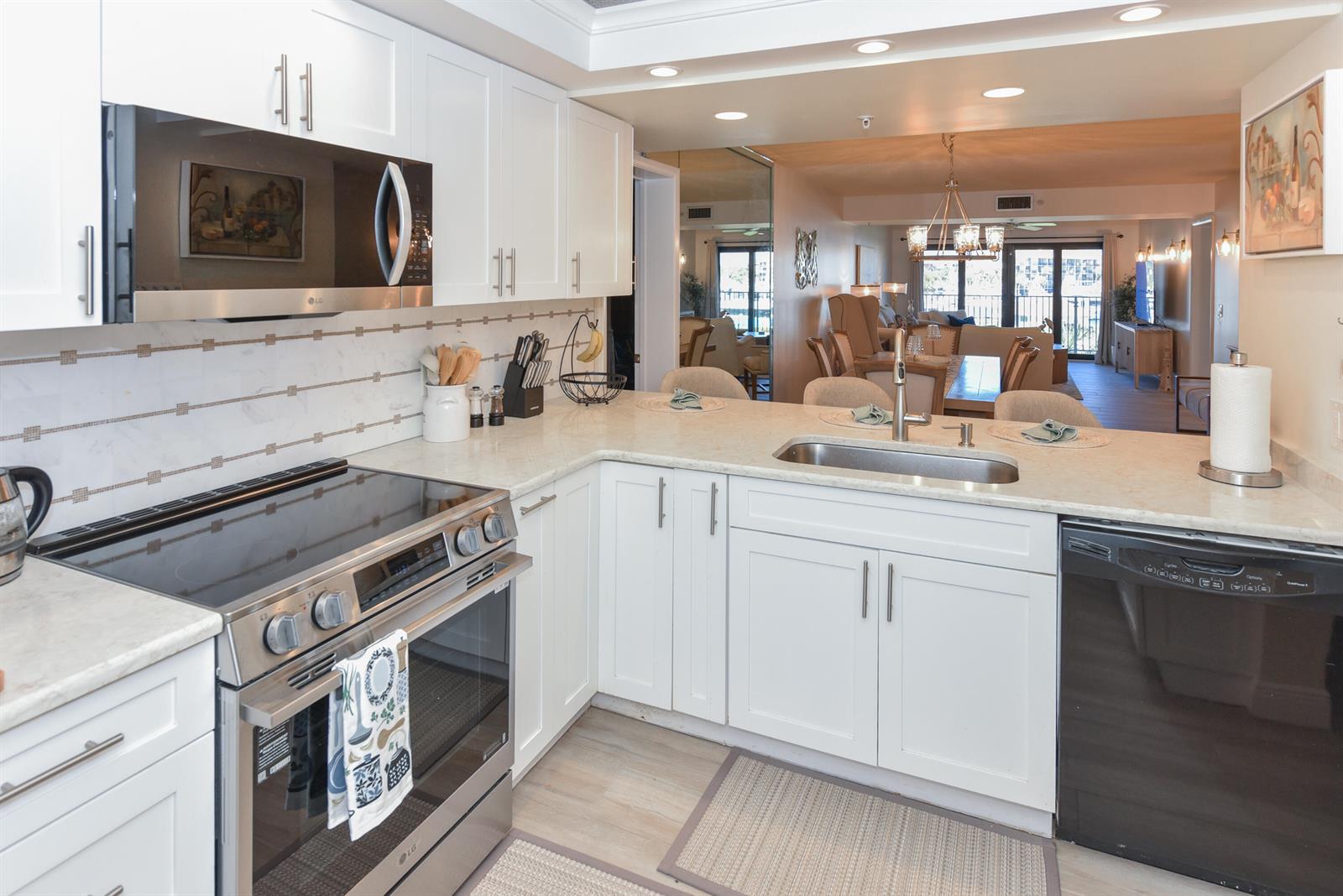 A white kitchen features stainless steel appliances, light countertops, and an open view into the living area — 901 Seafarer Circle # 302, Jupiter FL 33477, JUPITER, FL
