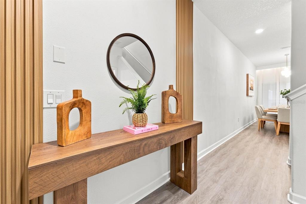 A wooden console table sits against a wall with vertical wood slats and a mirror — 4879 CLOCK TOWER DRIVE, KISSIMMEE, FL