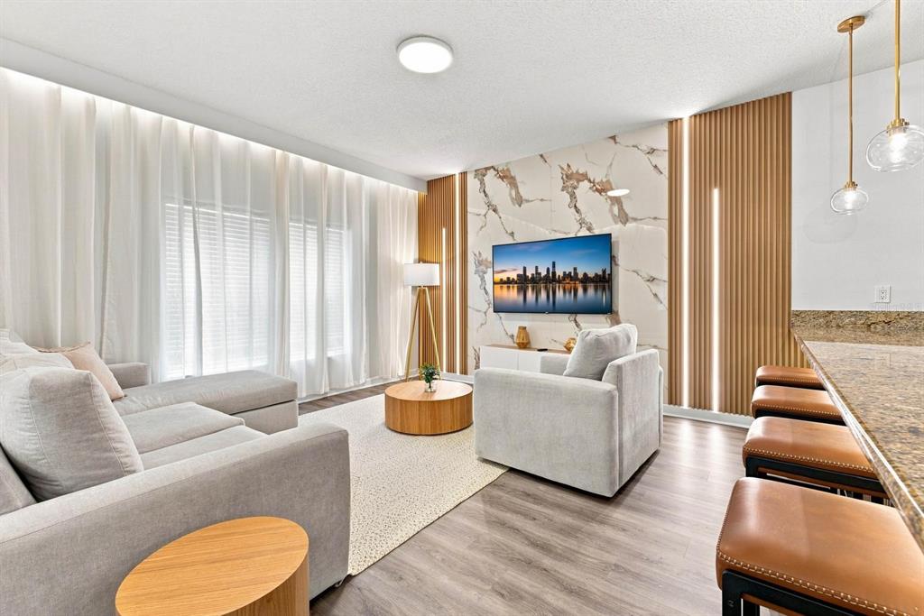 A living room features a marble accent wall, wood slat panels, and light-colored furniture — 4879 CLOCK TOWER DRIVE, KISSIMMEE, FL