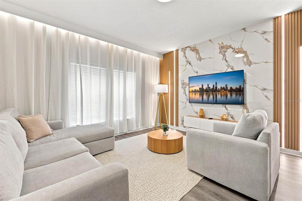 A living room features a marble accent wall, wood slat panels, and light gray furniture — 4879 CLOCK TOWER DRIVE, KISSIMMEE, FL