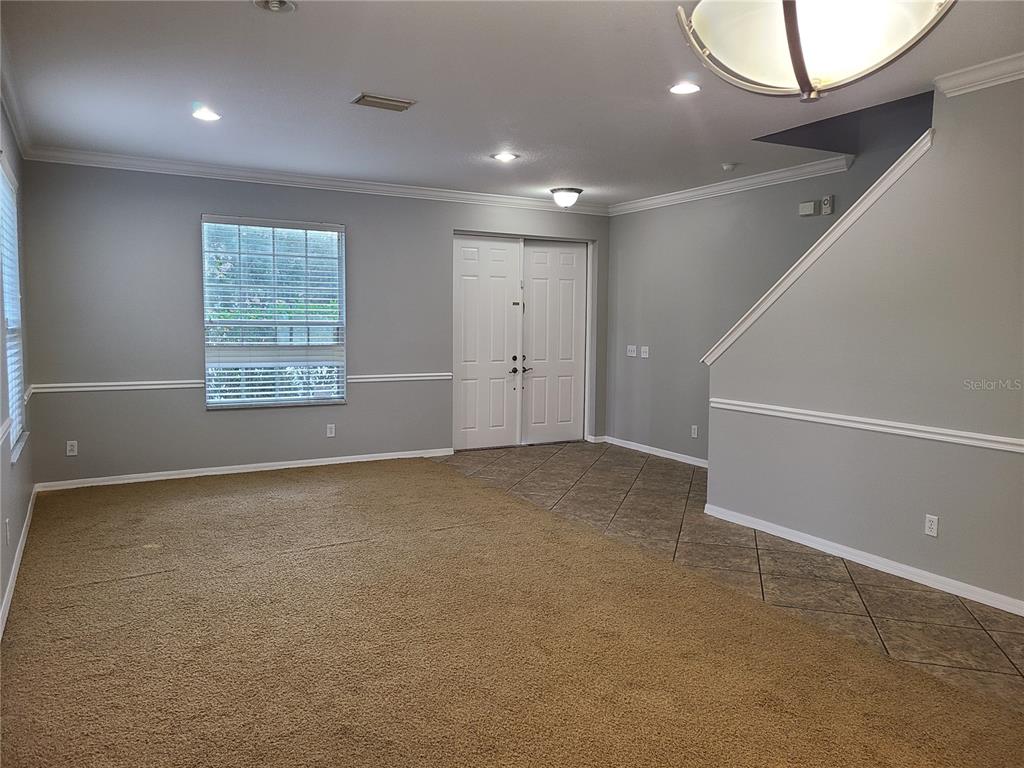 An interior view of a living room with carpet, tile flooring, and a staircase — 6122 39TH COURT E, BRADENTON, FL