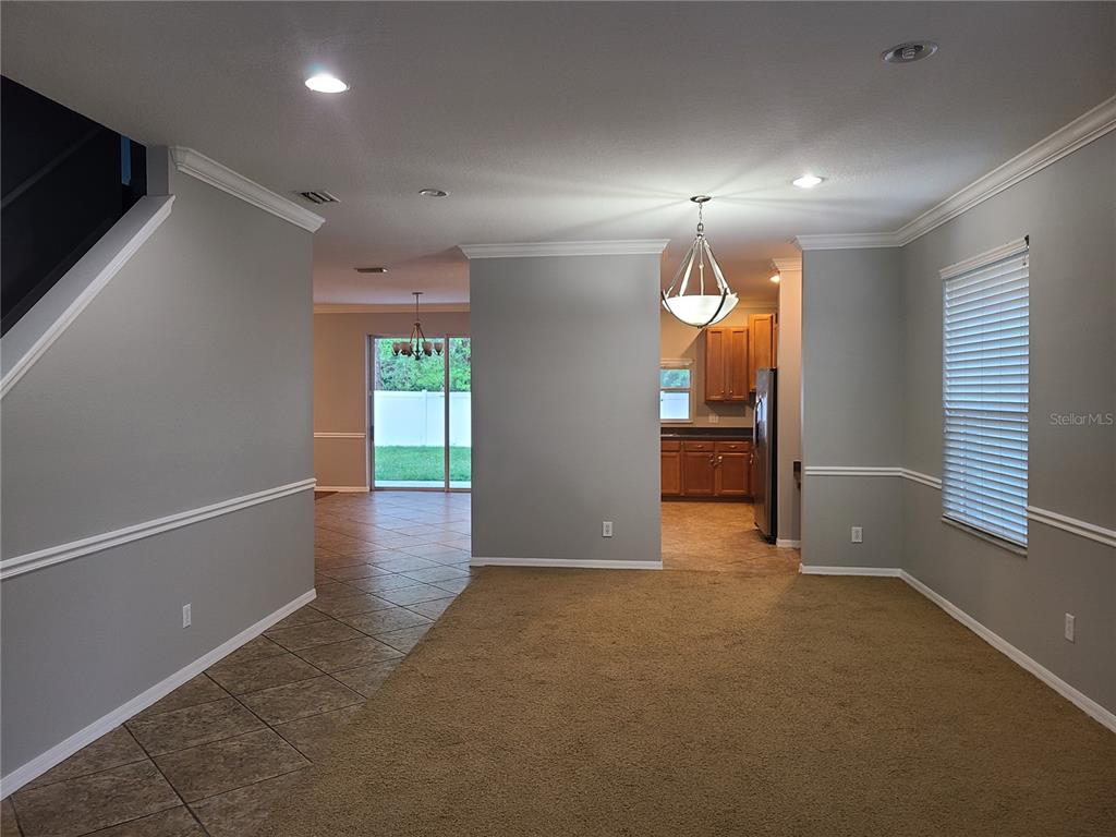 A living area with carpeted flooring transitions into a tiled dining space and kitchen — 6122 39TH COURT E, BRADENTON, FL