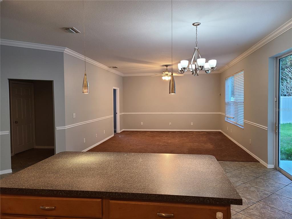 A kitchen island with a dark countertop overlooks a dining area with brown carpet — 6122 39TH COURT E, BRADENTON, FL