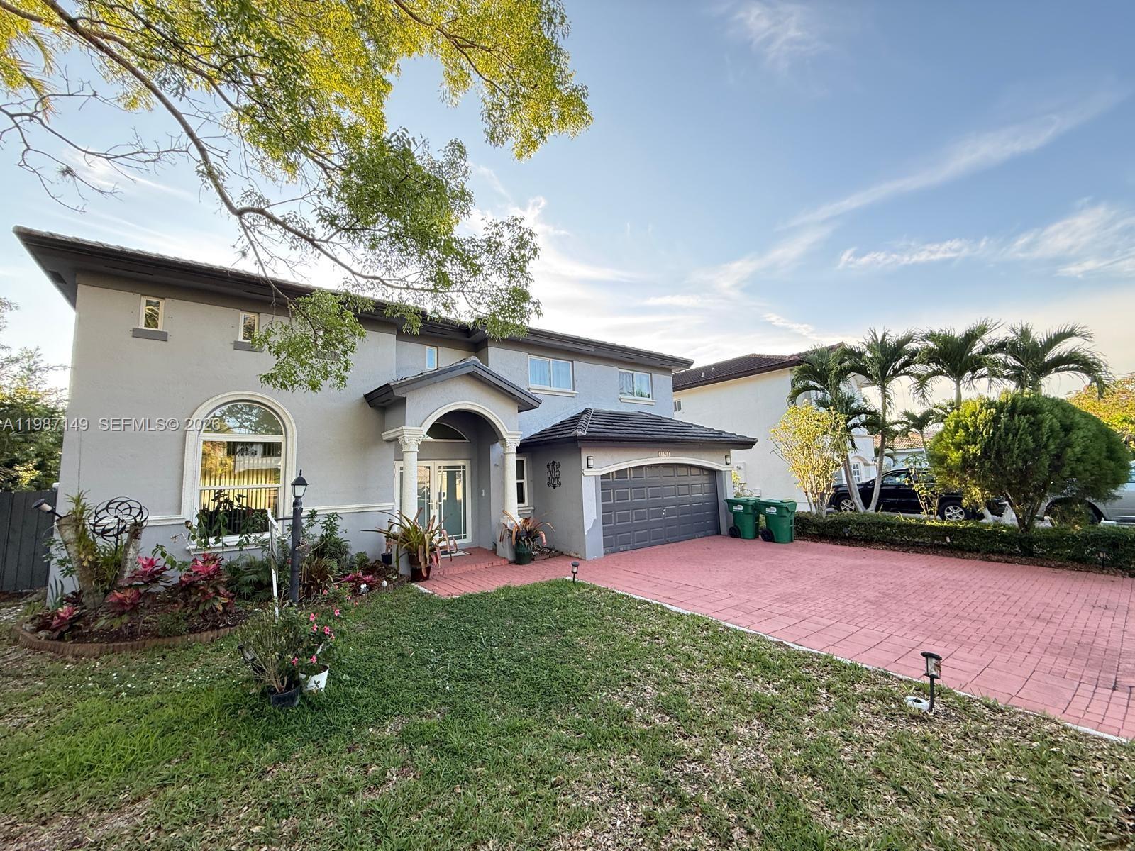 A two-story gray house features a red brick driveway, a garage, and a front lawn — 18164 SW 149th Pl, Miami FL 33187, MIAMI, FL