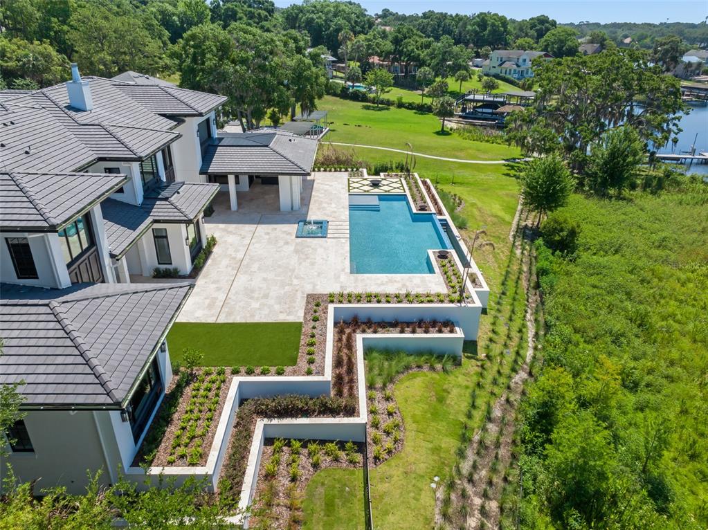 An aerial view shows a modern house with a pool, patio, and tiered garden beds — 3057 PORTO LAGO COURT, WINDERMERE, FL
