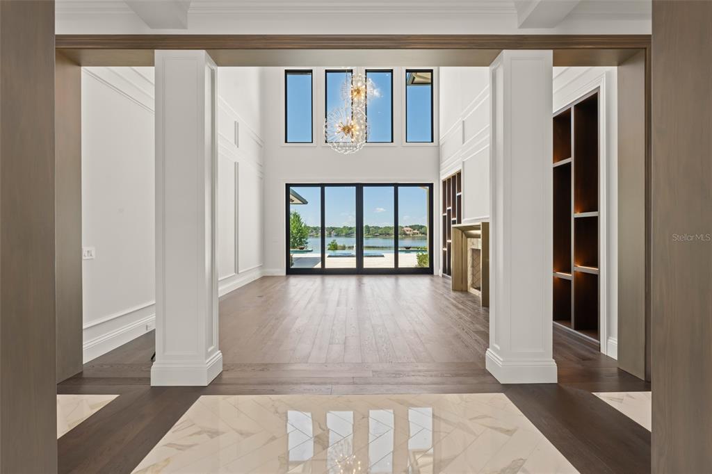 A view through a doorway into a living room with high ceilings and lake views — 3057 PORTO LAGO COURT, WINDERMERE, FL