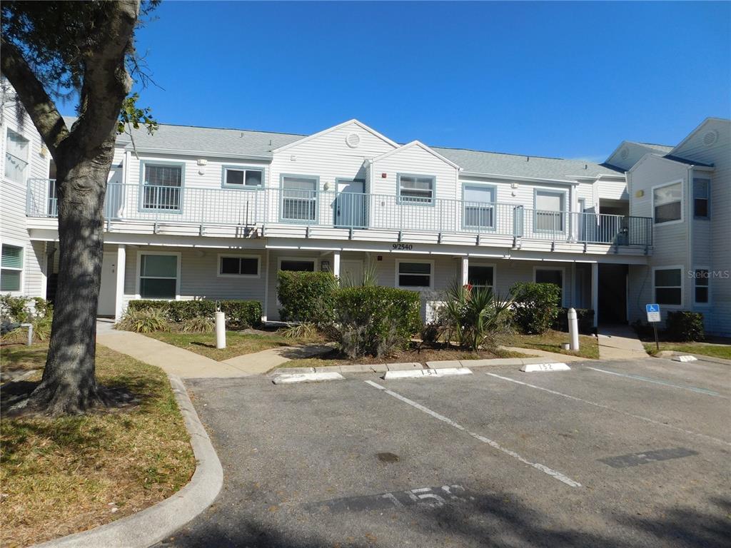 A two-story apartment building with white siding, a balcony, and a paved parking lot — 2540 WOODGATE BOULEVARD UNIT 204, ORLANDO, FL