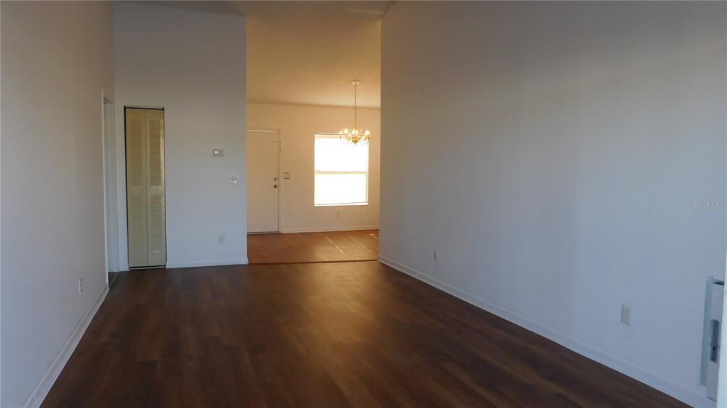 An empty room with wood-look flooring, white walls, and a view into an adjacent entryway — 2540 WOODGATE BOULEVARD UNIT 204, ORLANDO, FL