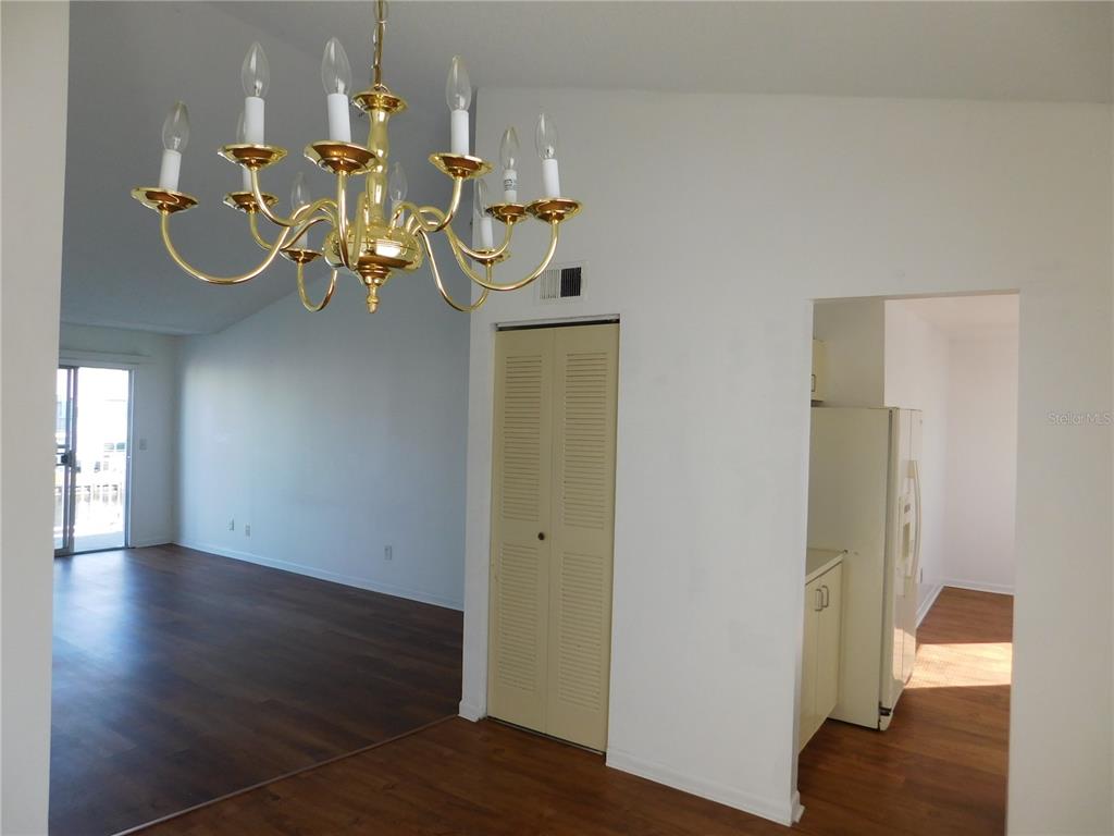 A dining area with a brass chandelier, a louvered closet door, and an adjacent kitchen — 2540 WOODGATE BOULEVARD UNIT 204, ORLANDO, FL