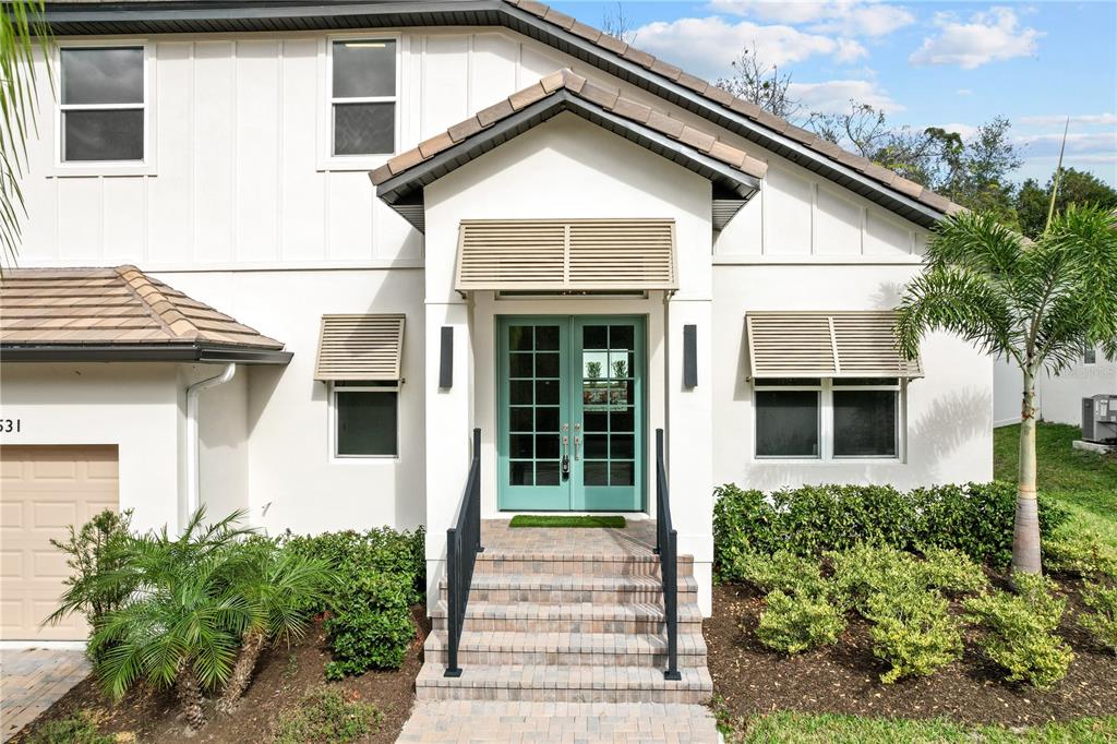 A white two-story house exterior features a teal double front door and brick steps — 531 SANCTUARY GOLF PLACE, APOPKA, FL
