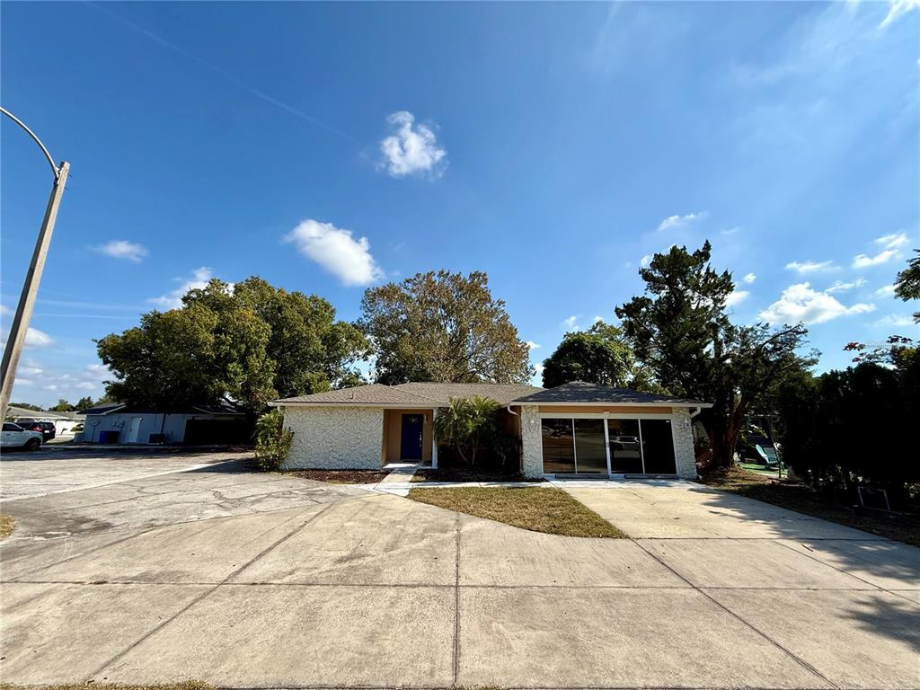 A single-story house with a concrete driveway, textured exterior walls, and a large front yard — 9330 REGENCY PARK BOULEVARD, PORT RICHEY, FL