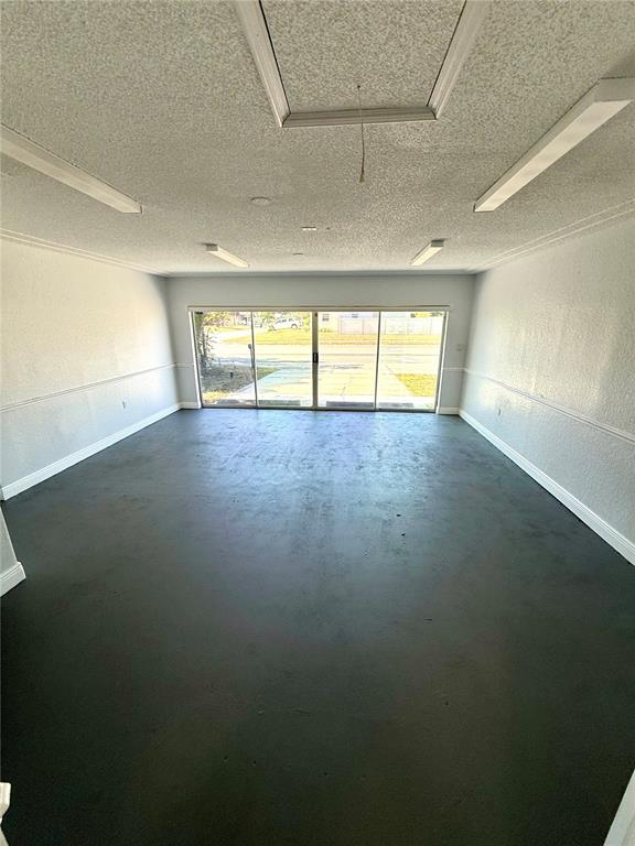 A spacious room with a dark floor, light walls, and sliding glass doors — 9330 REGENCY PARK BOULEVARD, PORT RICHEY, FL