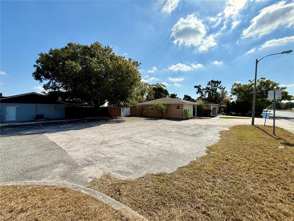 A large, cracked asphalt parking lot sits in front of two single-story residential buildings — 9330 REGENCY PARK BOULEVARD, PORT RICHEY, FL