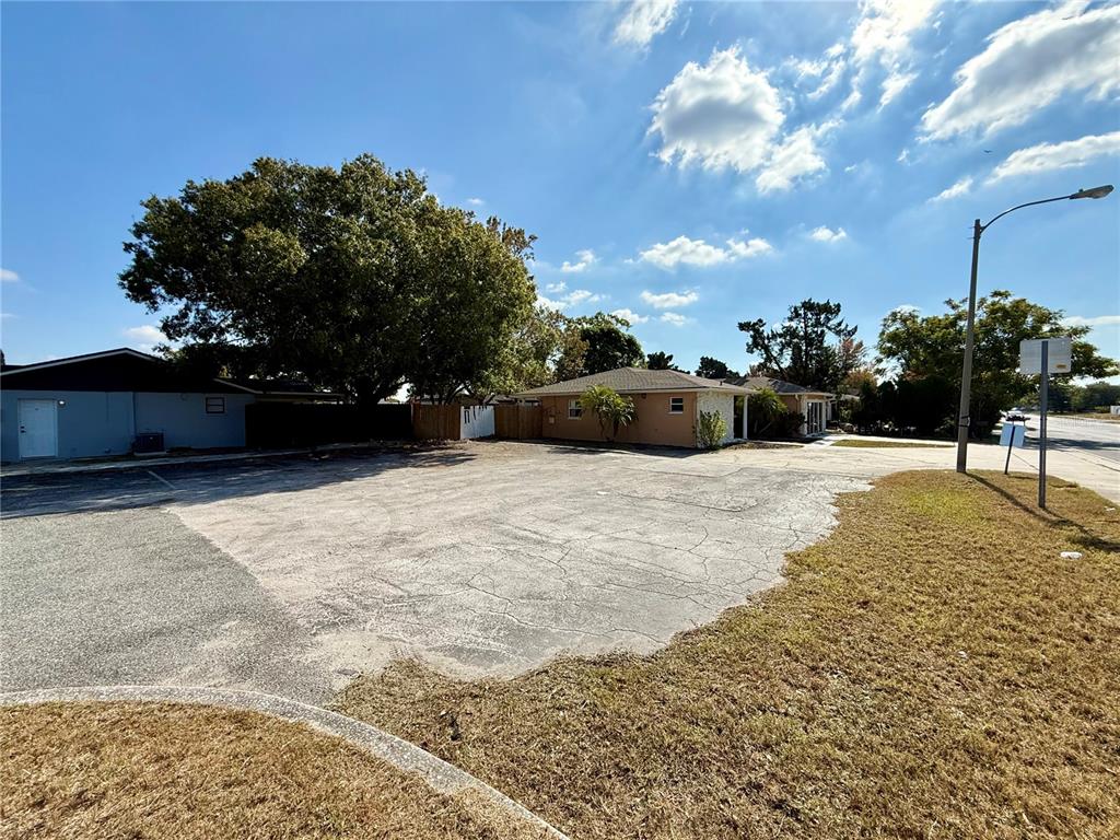 A large, cracked asphalt parking lot sits in front of a single-story residential building — 9330 REGENCY PARK BOULEVARD, PORT RICHEY, FL