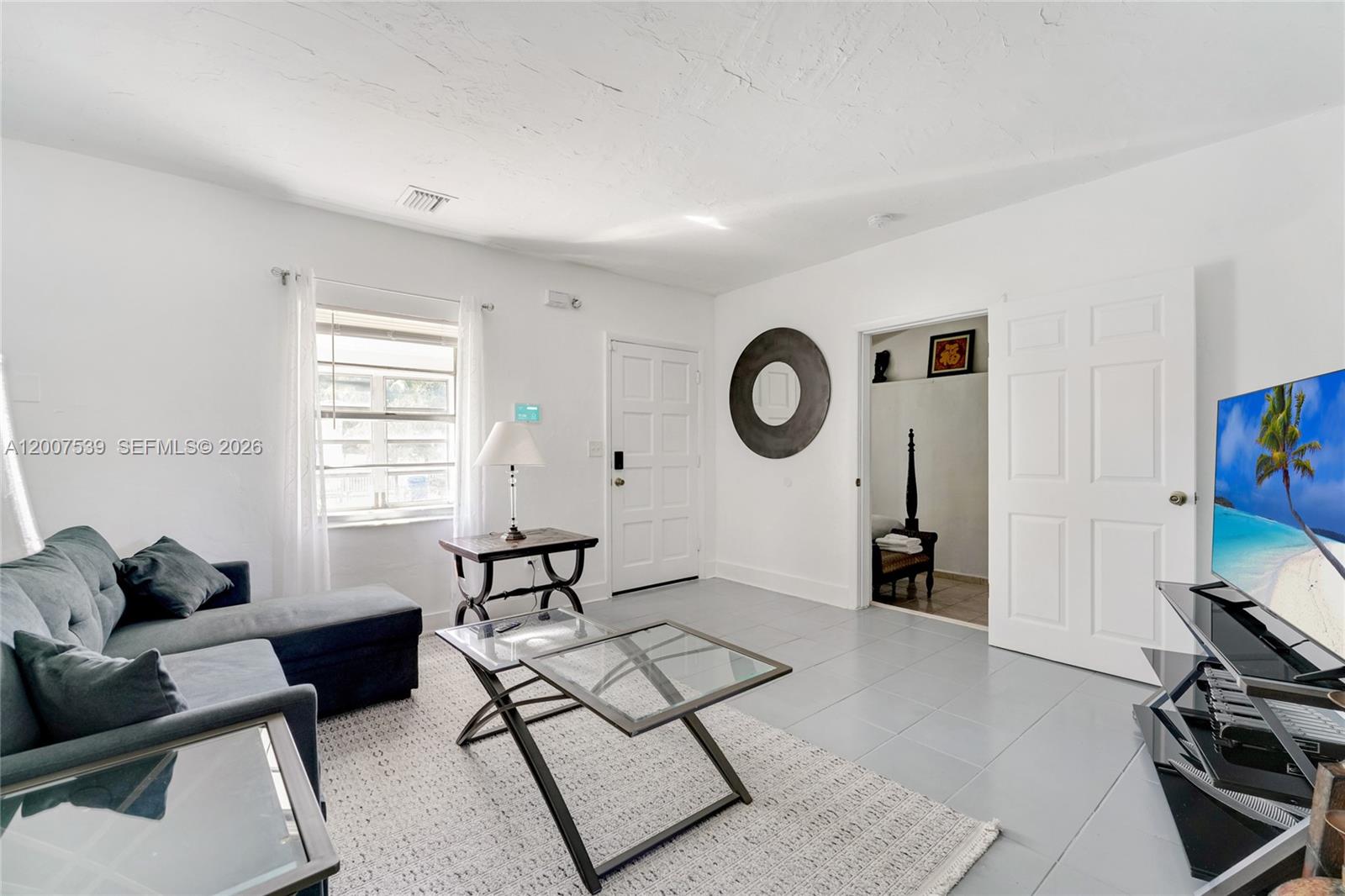 A living room features gray tile flooring, a sectional sofa, and a glass coffee table — 1283 NW 45th St, Miami FL 33142, MIAMI, FL