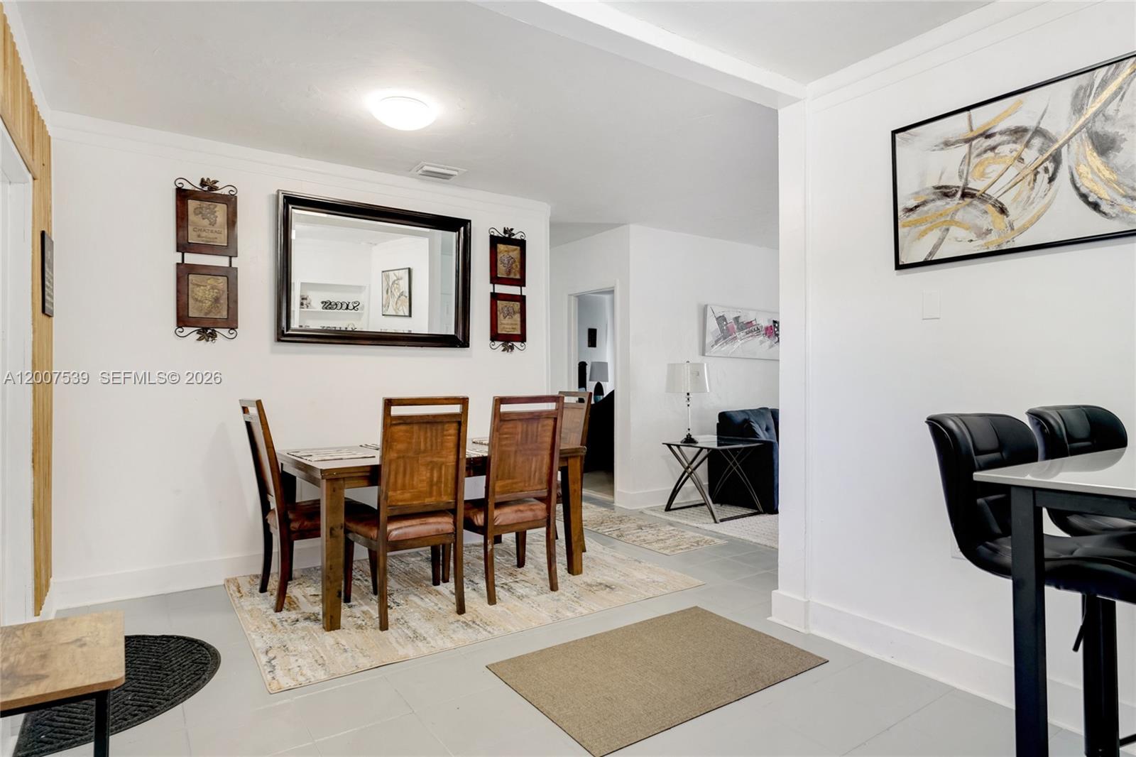 A dining area with a wooden table and chairs sits adjacent to a living room — 1283 NW 45th St, Miami FL 33142, MIAMI, FL