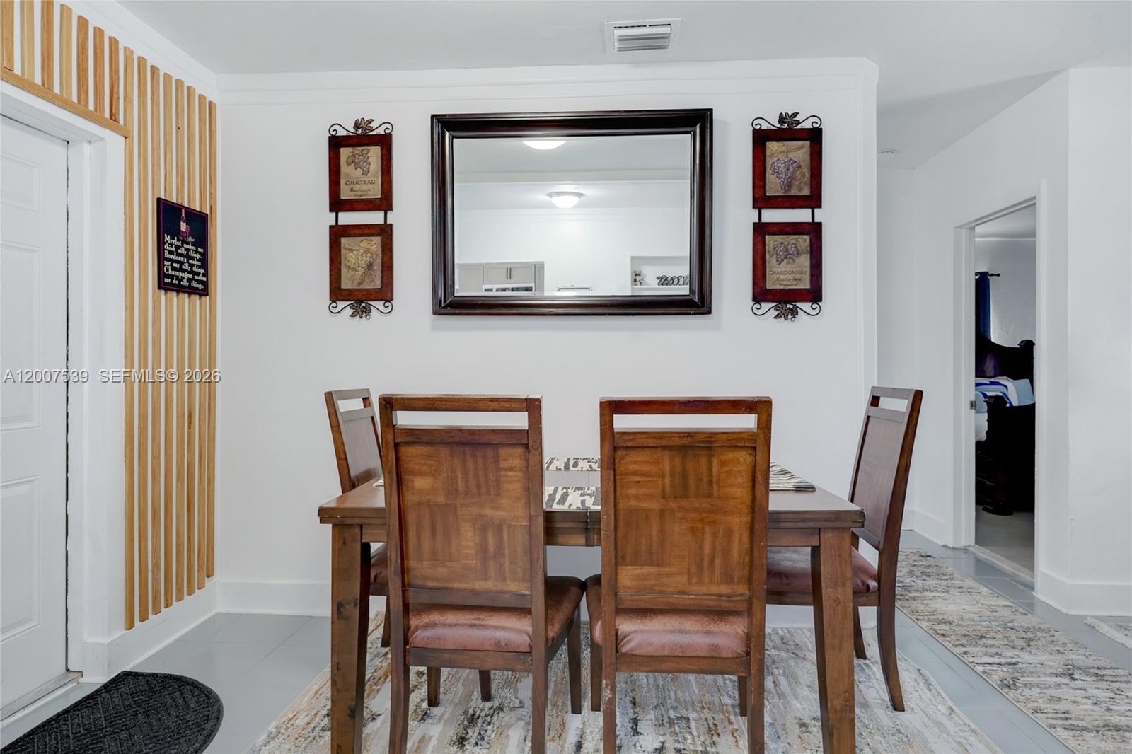 A dining room features a wooden table and chairs, a wall mirror, and decorative wall art — 1283 NW 45th St, Miami FL 33142, MIAMI, FL