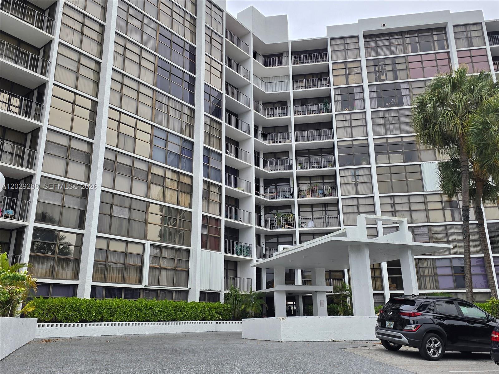 A multi-story apartment building features a white exterior, numerous glass balconies, and a covered entrance — 400 Leslie Dr # 416, Hallandale Beach FL 33009, HALLANDALE BEACH, FL