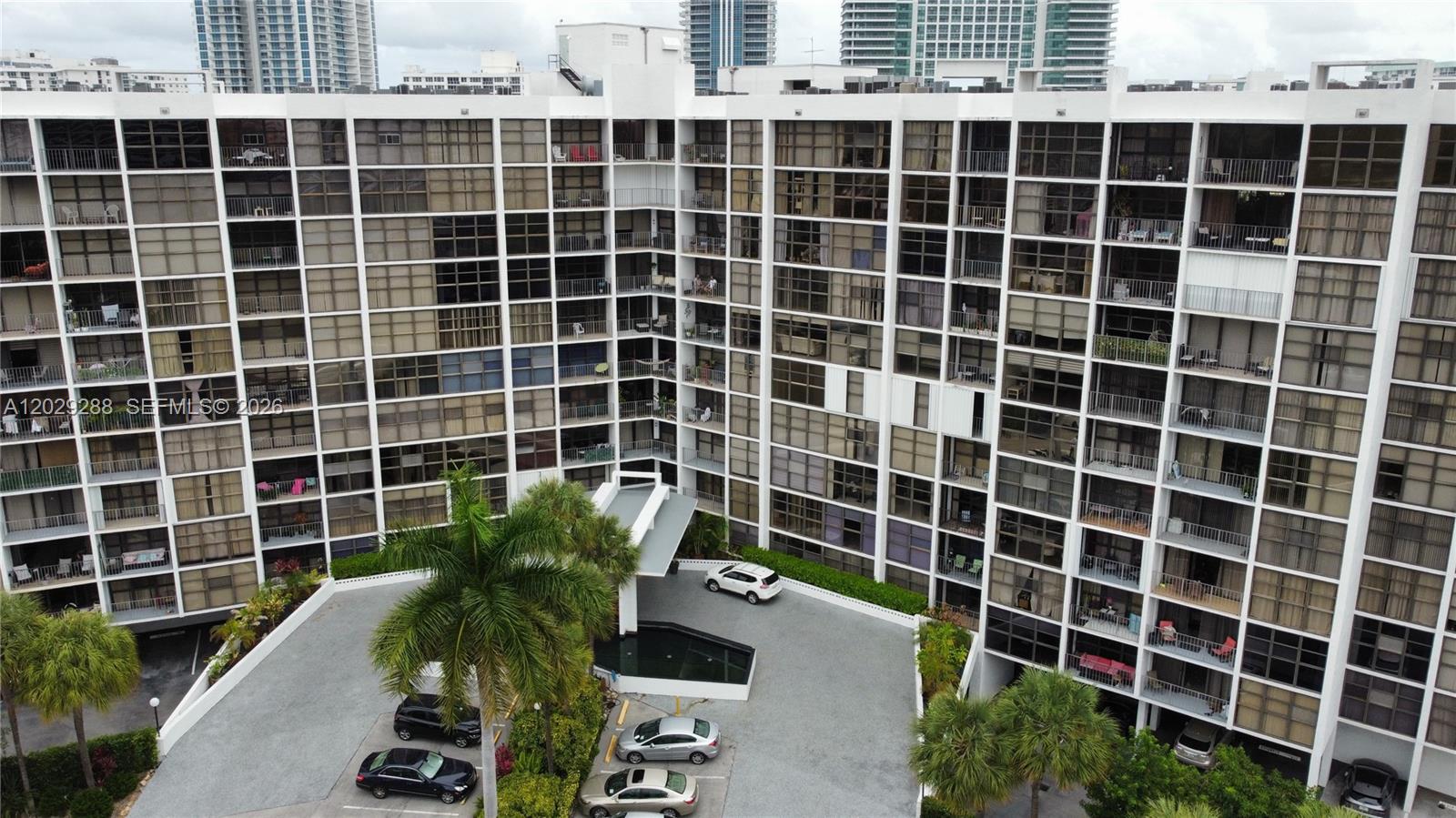 An aerial view shows the exterior of a multi-story apartment building with a parking area — 400 Leslie Dr # 416, Hallandale Beach FL 33009, HALLANDALE BEACH, FL