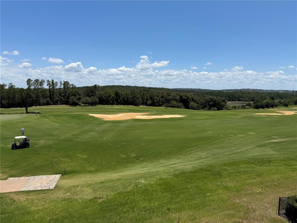 A view of a golf course fairway with sand bunkers, trees, and a golf cart — 16038 VETTA DRIVE, BELLA COLLINA, FL