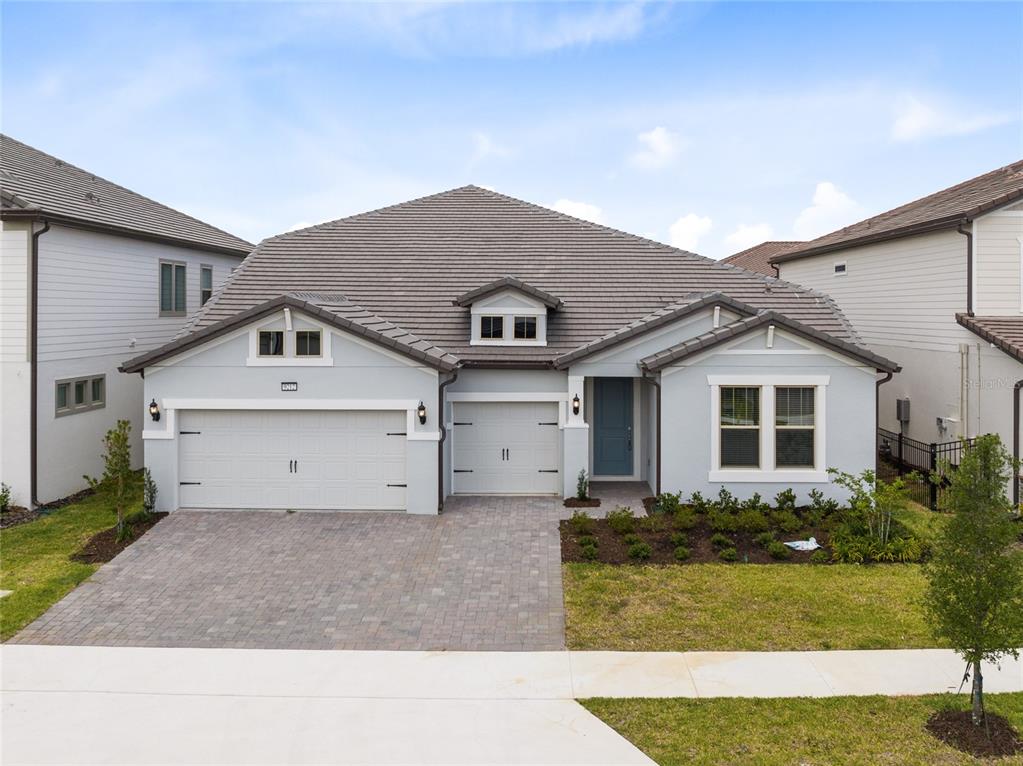 A light blue single-story house features a three-car garage, a tiled roof, and a paved driveway — 9212 HANGING VINE COURT, ORLANDO, FL