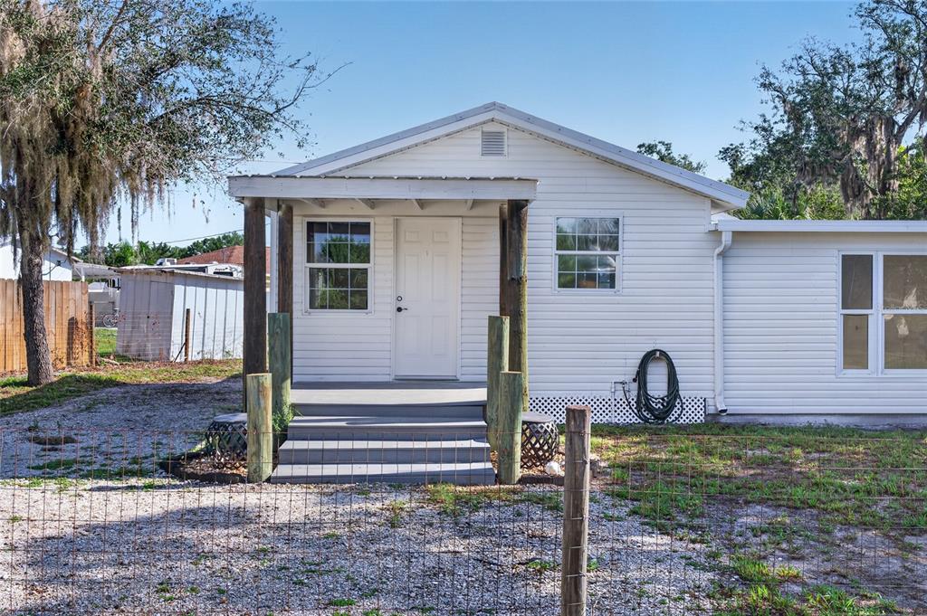 A white house with a covered front porch and wooden support posts sits behind fencing — 8024 HILLMAN AVENUE, PUNTA GORDA, FL