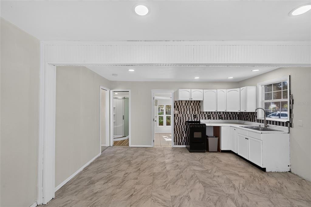 A kitchen with white cabinets, a black stove, and patterned tile flooring — 8024 HILLMAN AVENUE, PUNTA GORDA, FL