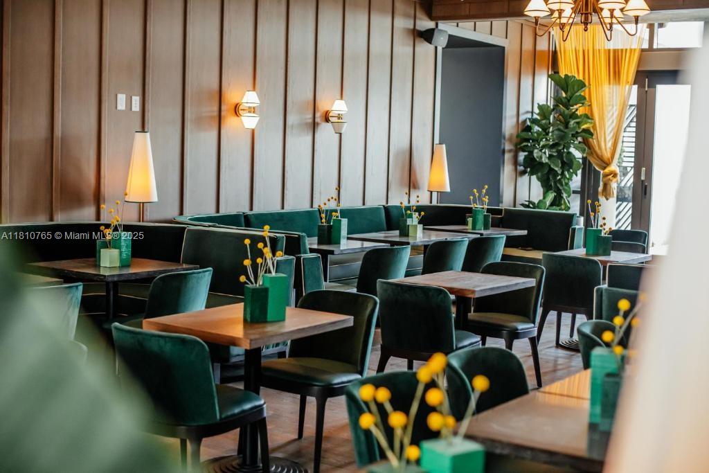 A restaurant dining room features dark wood paneling, green velvet chairs, and yellow floral centerpieces — 159 NE 6TH ST # 3205, Miami FL 33132, MIAMI, FL
