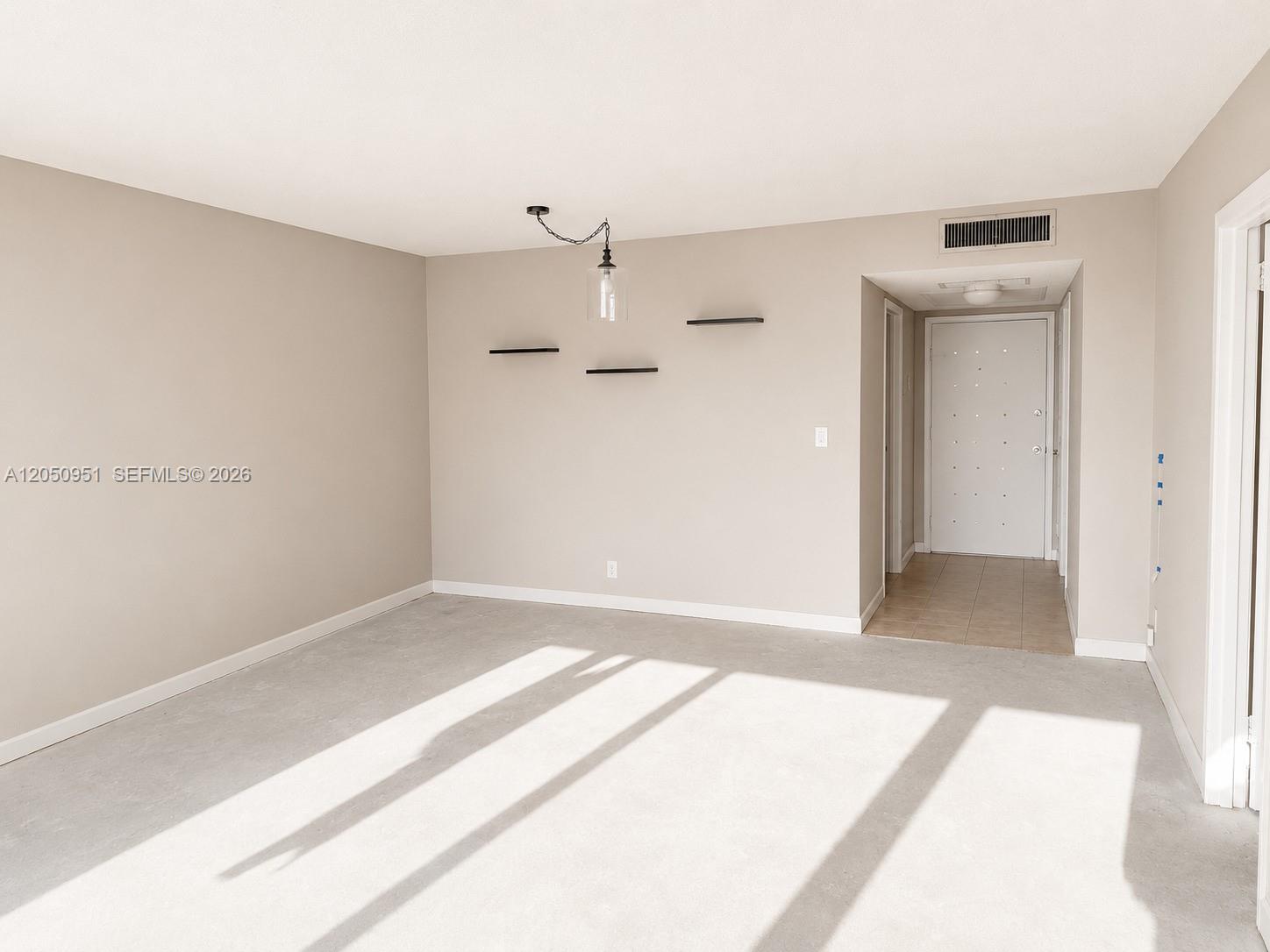 An empty room features beige walls, carpeted flooring, a pendant light, and floating shelves — 2030 S Ocean Dr # 1503, Hallandale Beach FL 33009, HALLANDALE BEACH, FL