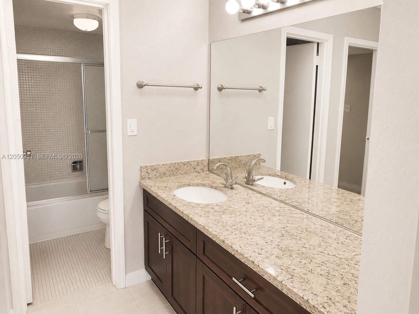 A bathroom features a dark wood vanity with a granite countertop and a mirror — 2030 S Ocean Dr # 1503, Hallandale Beach FL 33009, HALLANDALE BEACH, FL