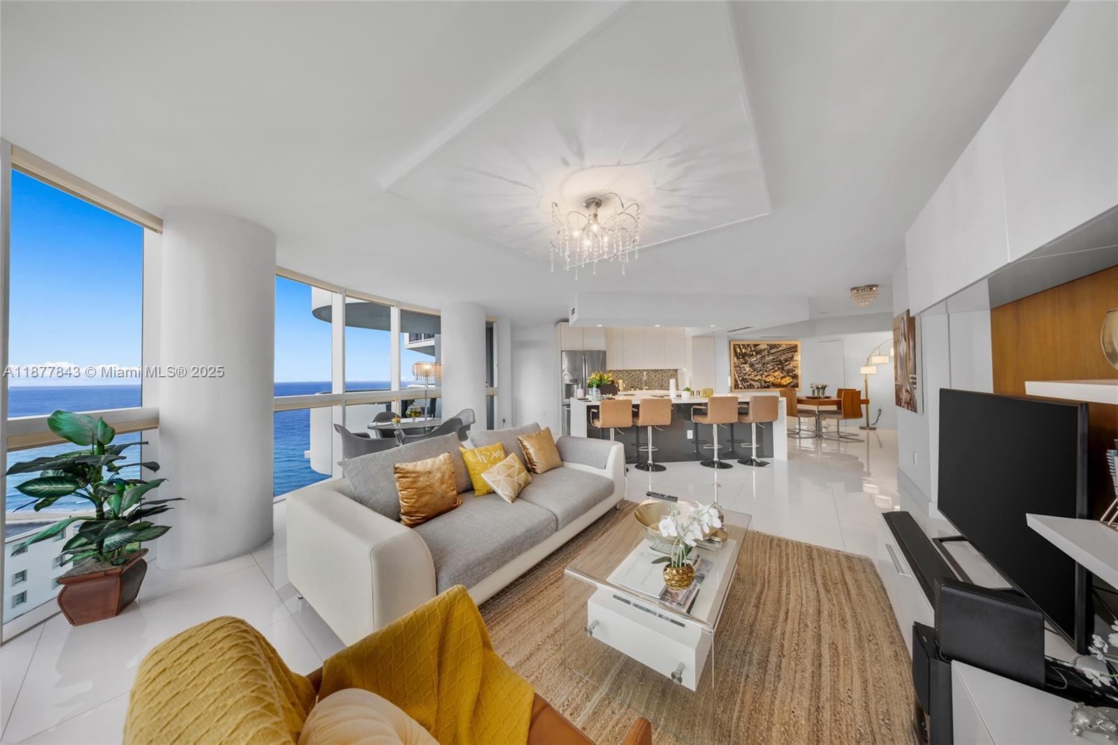 A modern living room with ocean views, a gray sofa, and an open kitchen area — 6301 Collins Ave # 2107, Miami Beach FL 33141, MIAMI BEACH, FL