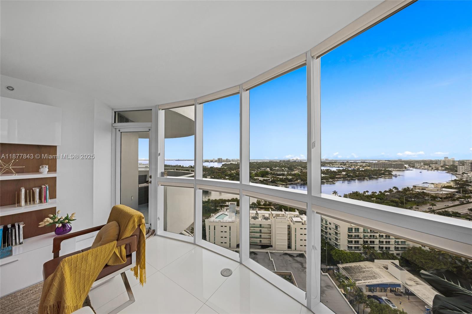 A bright room with white tile floors, built-in shelving, and floor-to-ceiling windows overlooking water — 6301 Collins Ave # 2107, Miami Beach FL 33141, MIAMI BEACH, FL