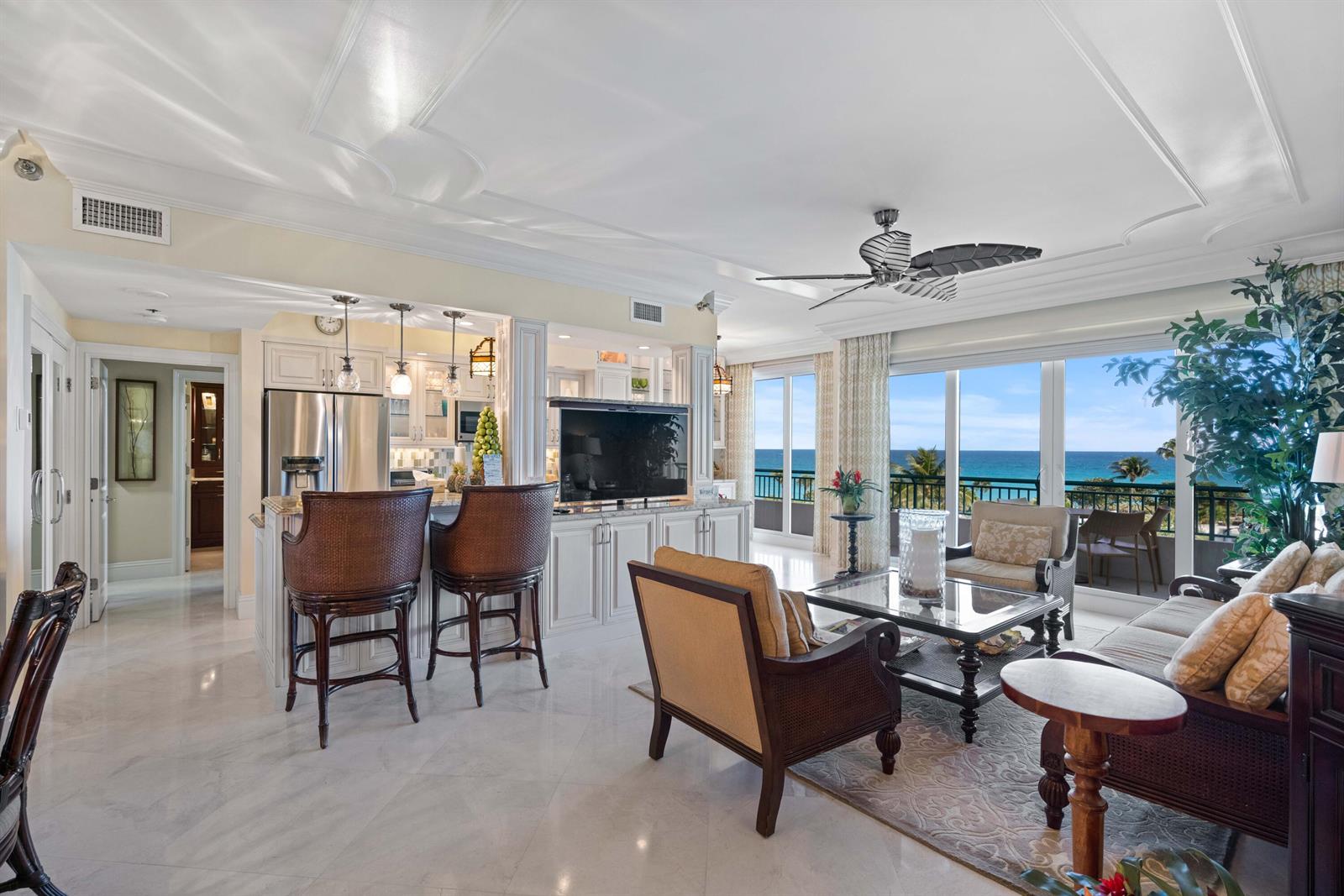 An open-concept living room and kitchen feature white cabinetry, marble floors, and ocean views — 2000 S Highway A1a # 406, Jupiter FL 33477, JUPITER, FL