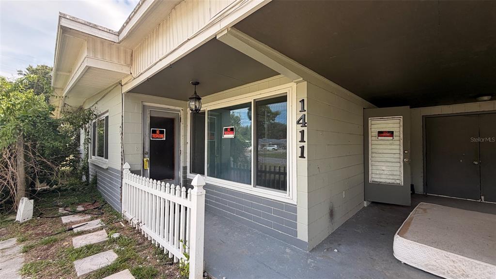 The exterior of a house features a covered porch, a white fence, and a mattress — 1411 LAKESHORE DRIVE, INVERNESS, FL