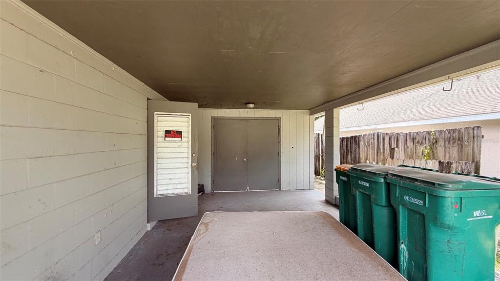 A covered patio area features a concrete floor, a storage closet, and three trash bins — 1411 LAKESHORE DRIVE, INVERNESS, FL