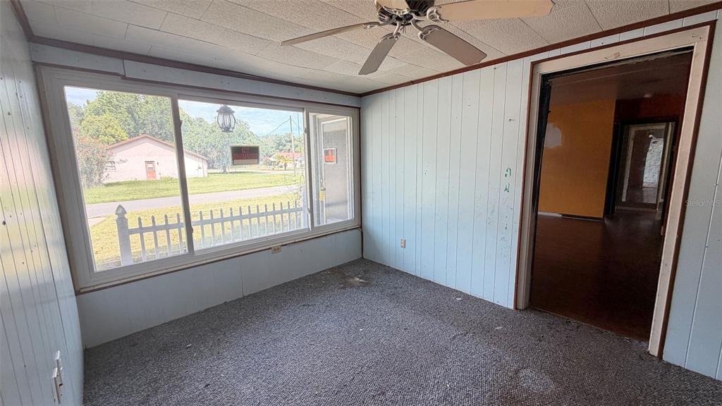 A sunroom with light blue wood paneling, gray carpet, a ceiling fan, and a large window — 1411 LAKESHORE DRIVE, INVERNESS, FL