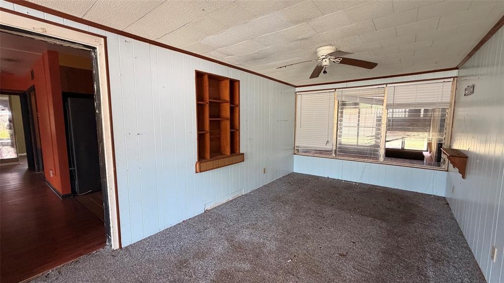 A room with light blue paneling, a ceiling fan, carpeted flooring, and built-in wooden shelving — 1411 LAKESHORE DRIVE, INVERNESS, FL