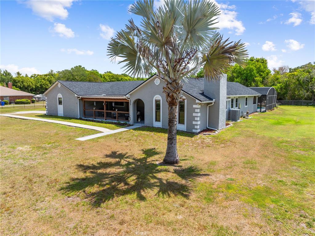 A single-story gray house with a covered porch, a palm tree, and a screened pool — 233 EASTERN AVENUE, ST CLOUD, FL