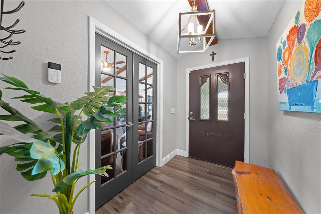 An entryway features a brown front door, French doors, a wooden bench, and a light fixture — 233 EASTERN AVENUE, ST CLOUD, FL