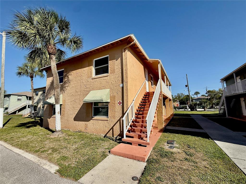 A two-story tan apartment building features an exterior staircase and a palm tree — 733 MICHIGAN COURT UNIT 4, ST CLOUD, FL